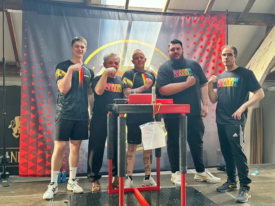 Cinq membres du club réunis autour d’une table de bras de fer